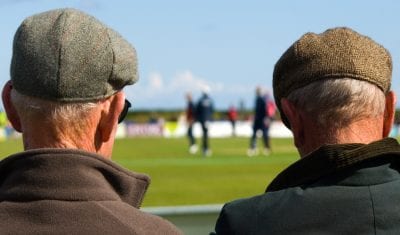 Two older men watching a football match