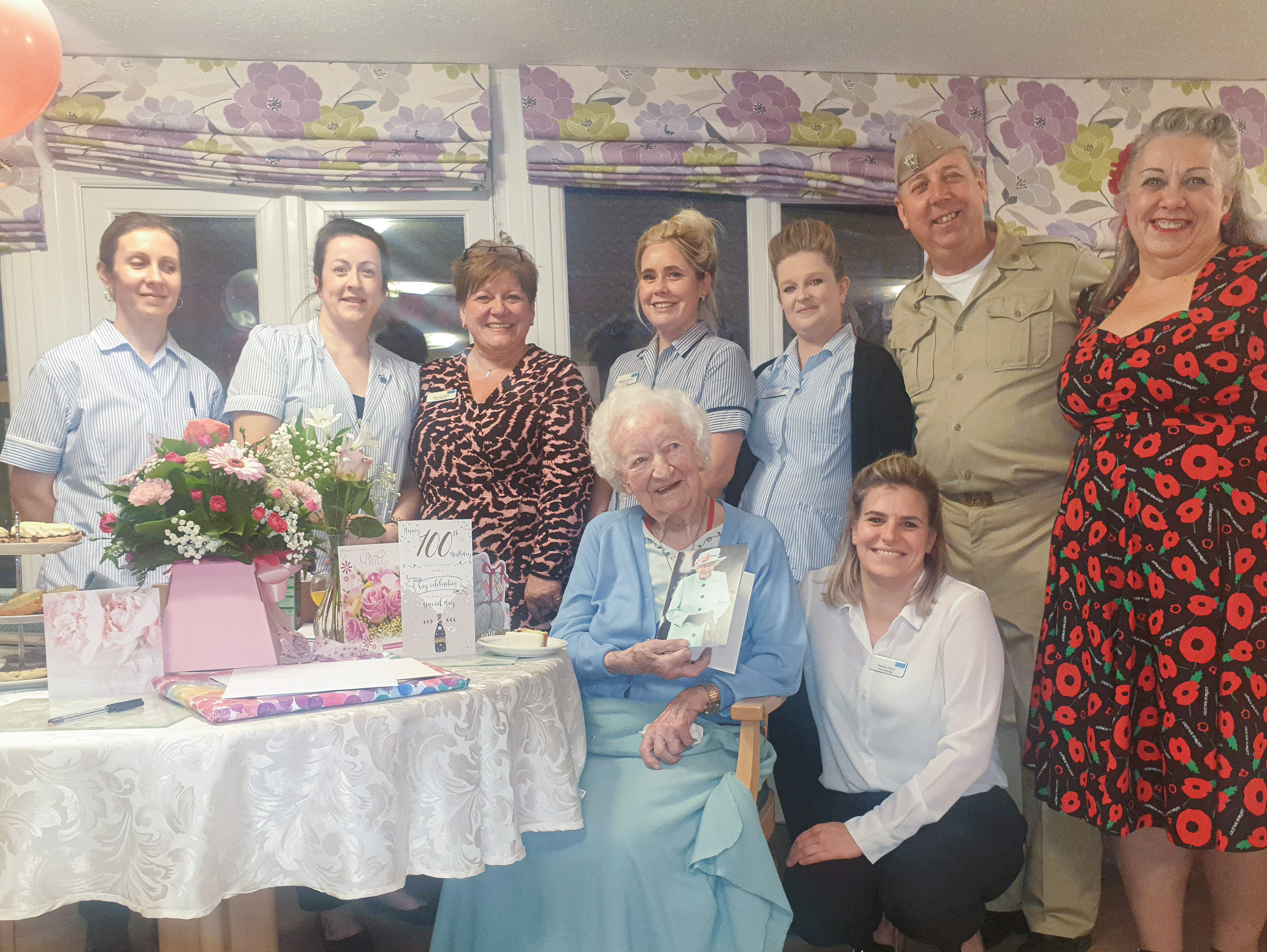 New Copford Place care home staff and Air Raid Jive posing with Marjorie at her birthday party