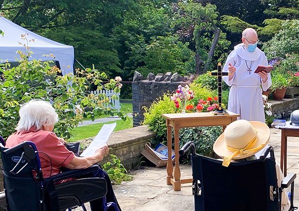 A priest stood in the garden with residents at a safe distance during the church service