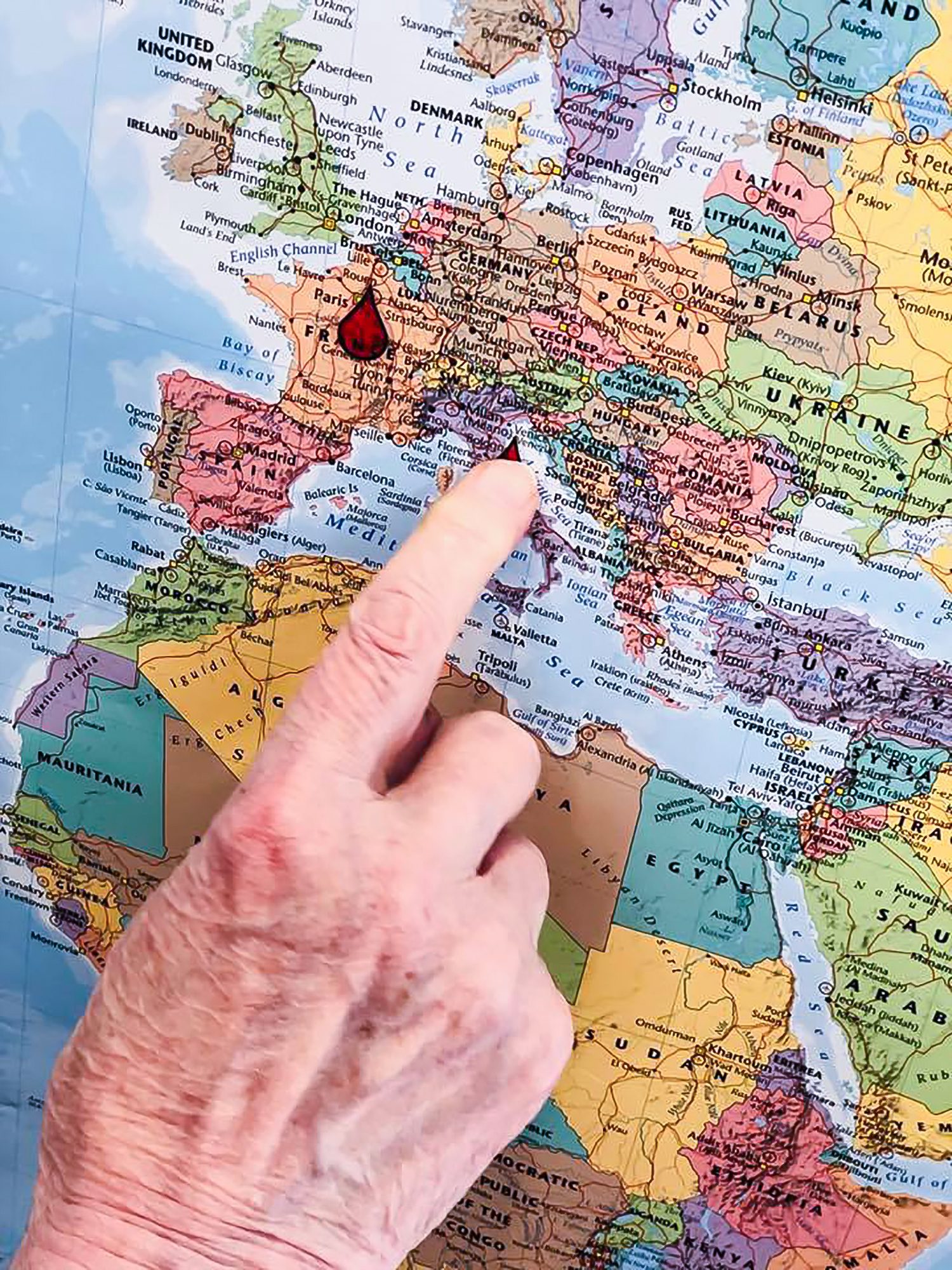 A resident's hand pointing to a world map