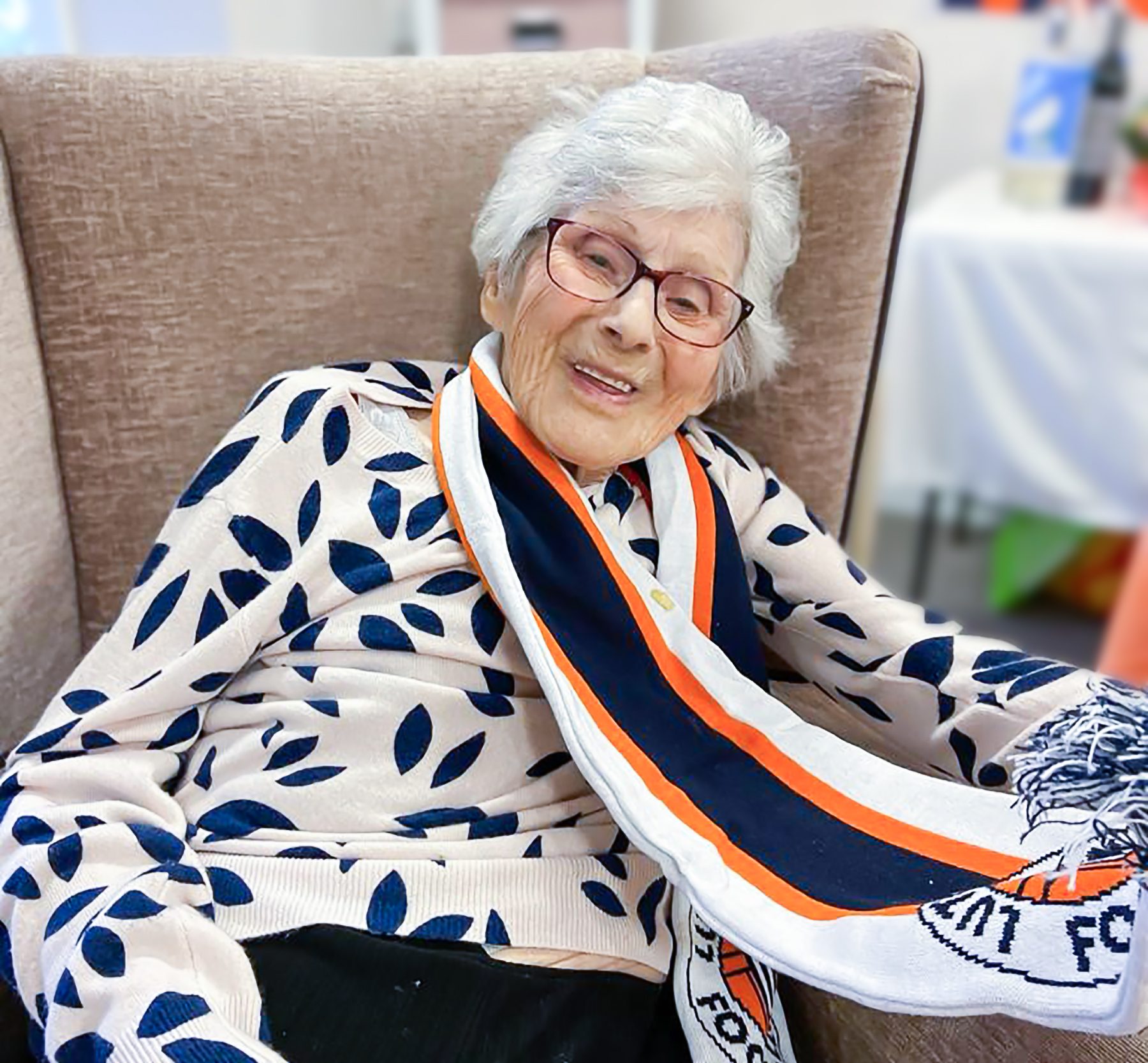 Little Bramingham Farm care home resident smiling and wearing her Hatter's scarf