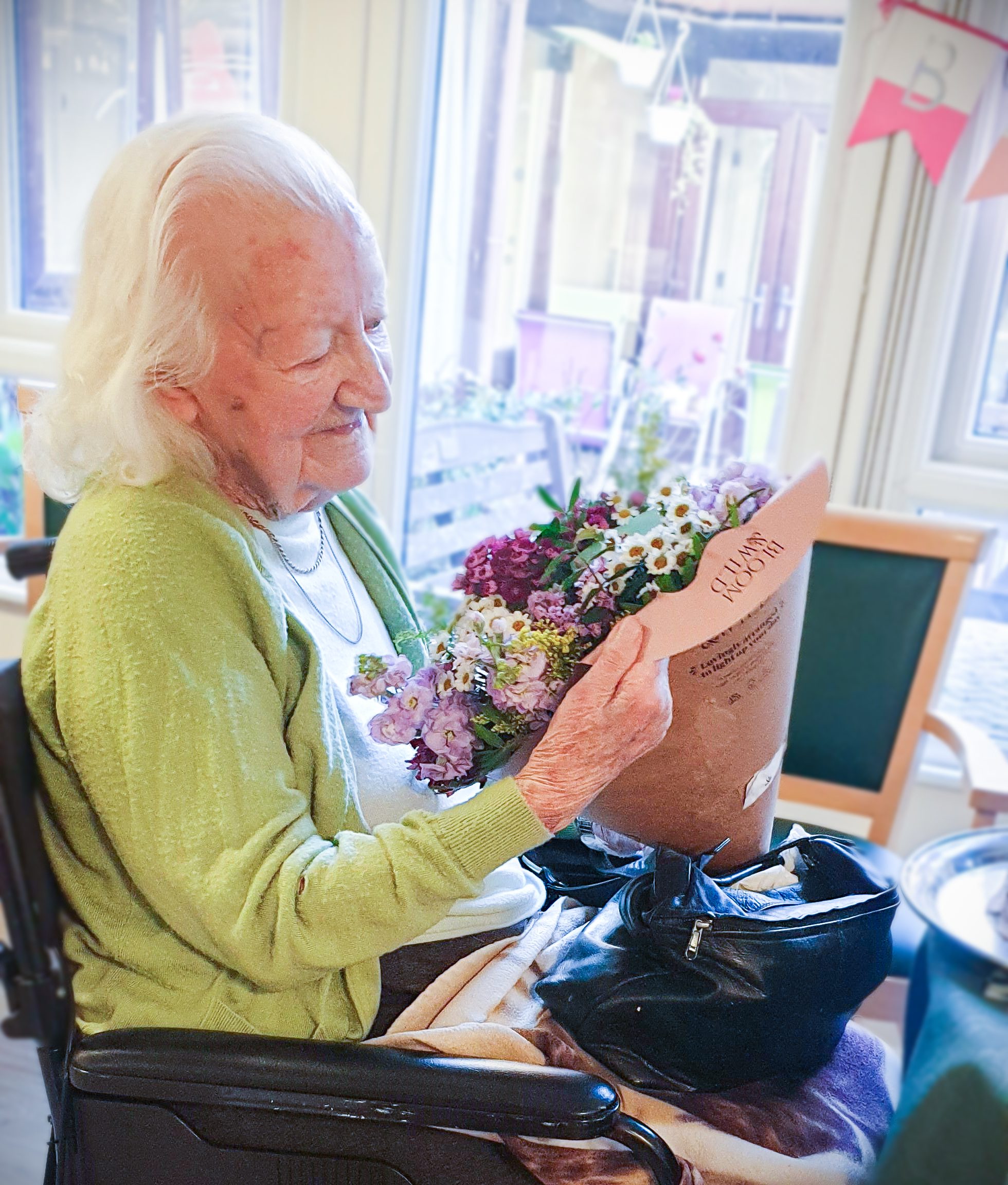 Essex resident Marjorie Wood celebrating her landmark birthday and looking at a bunch of flowers given to her as a gift. 