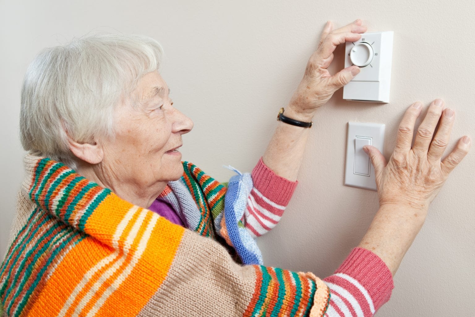 Senior woman adjusting her thermostat