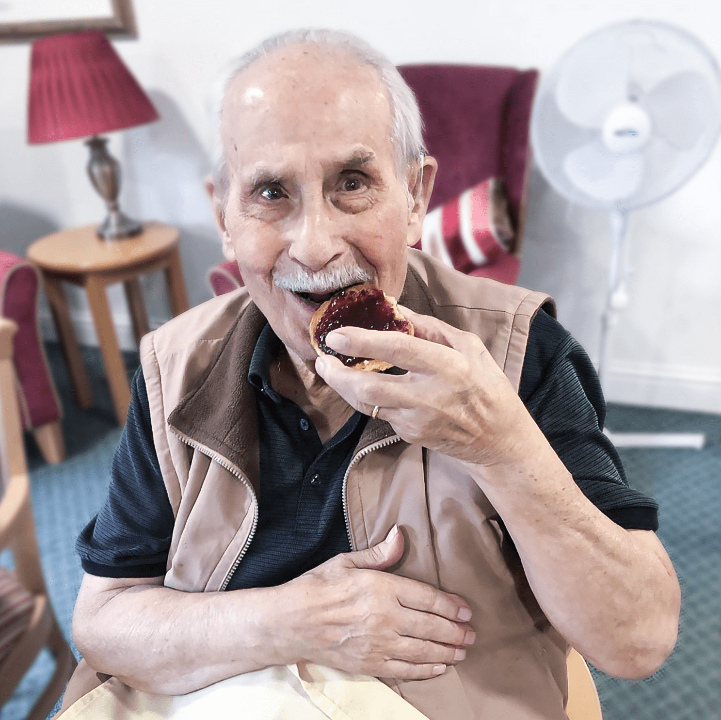 A Bernard Sunley care home resident eating a scone 