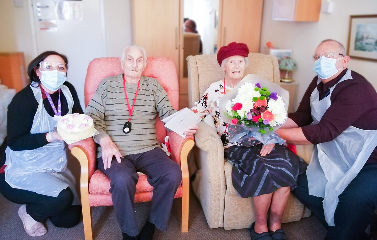 Len and Delia being presented with flowers and a cake on their wedding anniversary