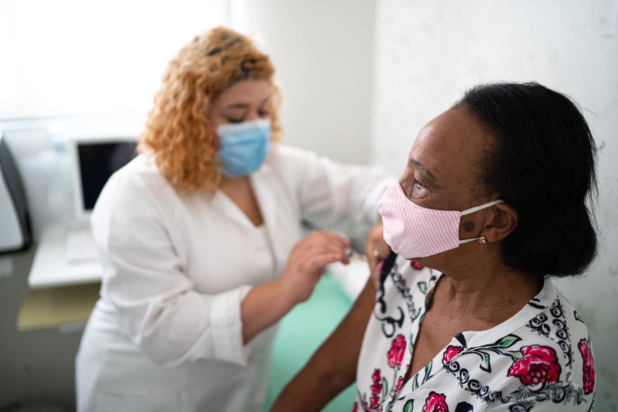 An older person receiving a vaccine from a health worker