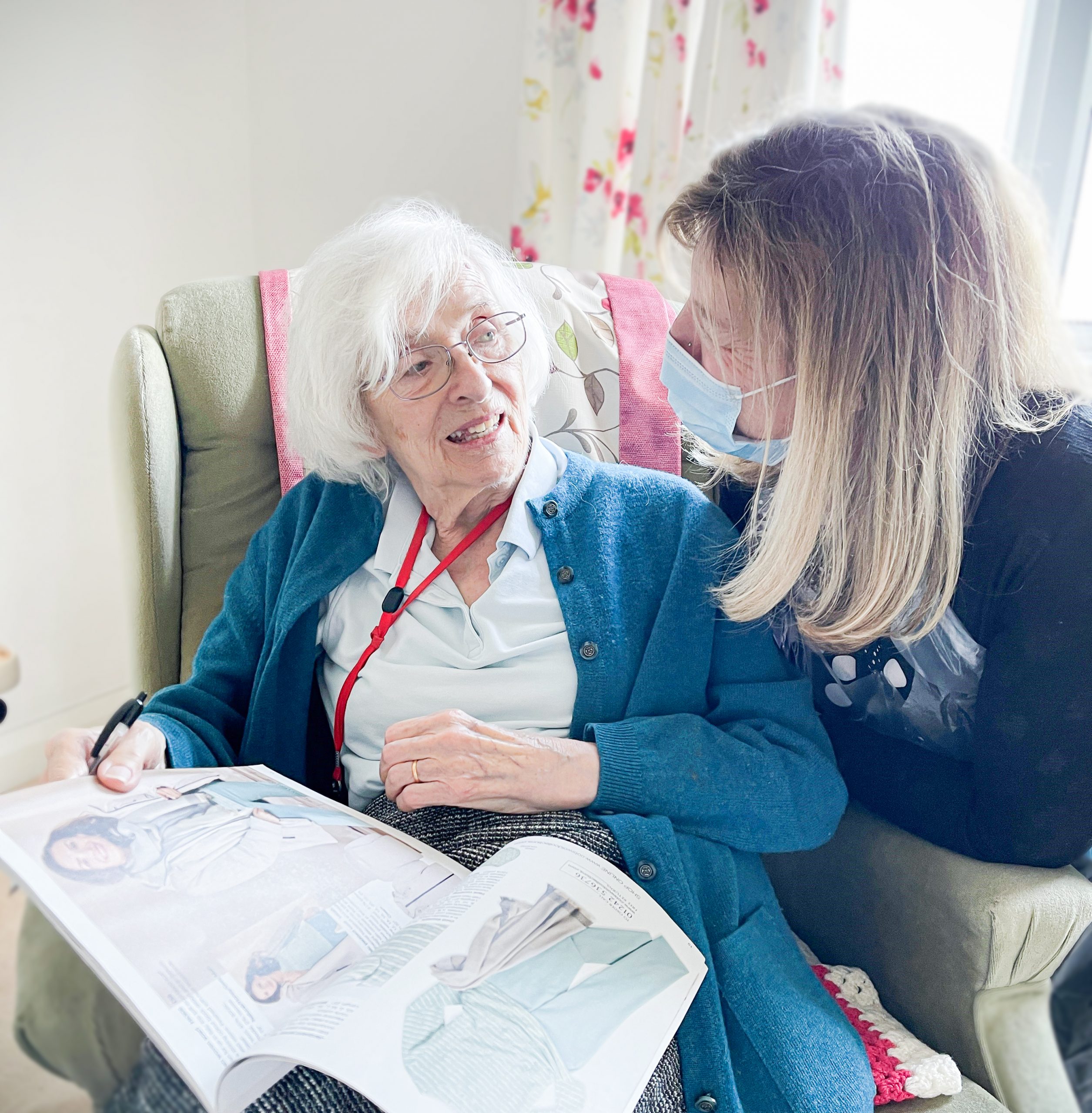 Respite care resident Felicity with Care Home Manager Jan sat together reading a magazine