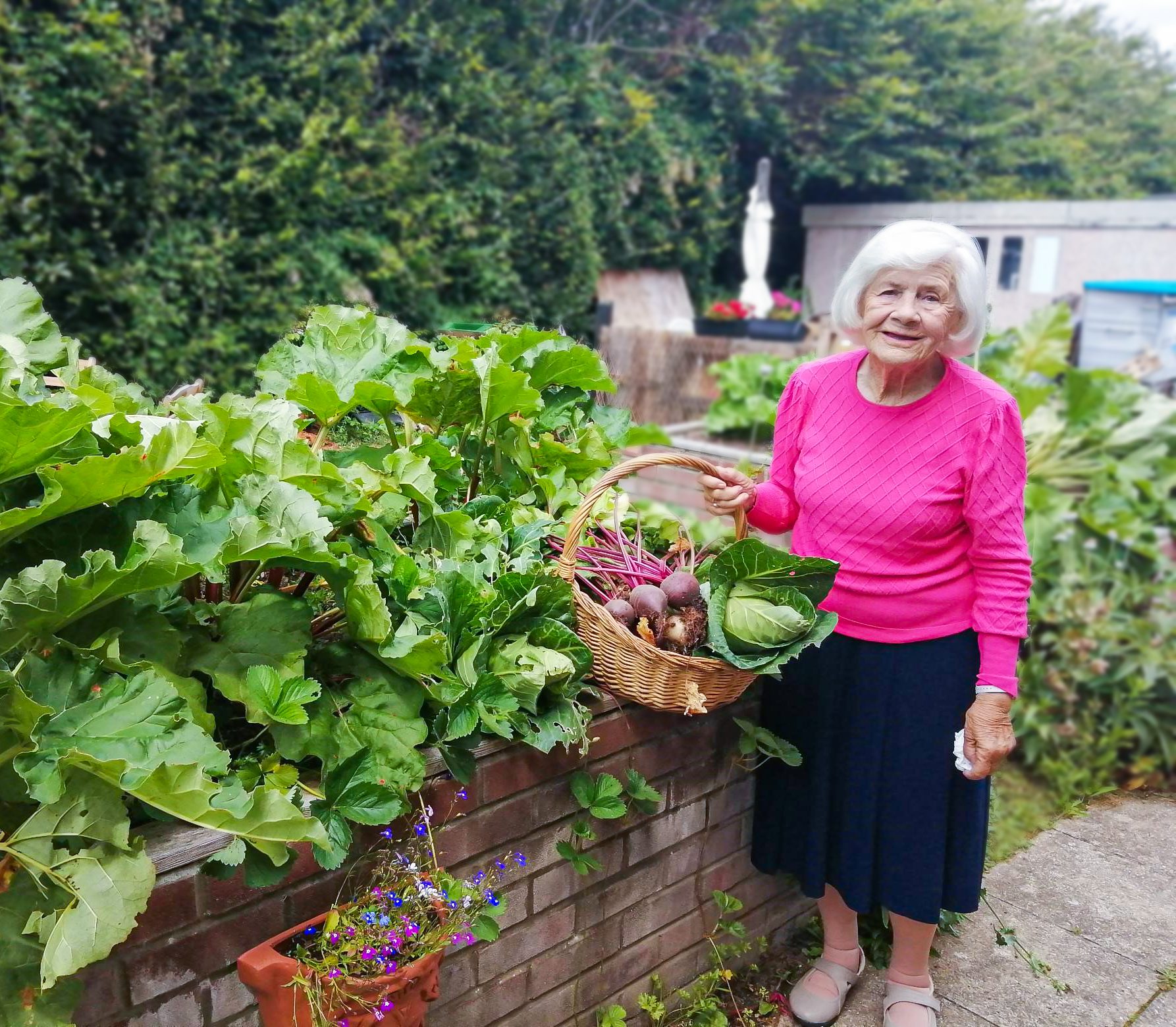 RNNH care home resident holding a basket full of freshly harvested vegetables. 