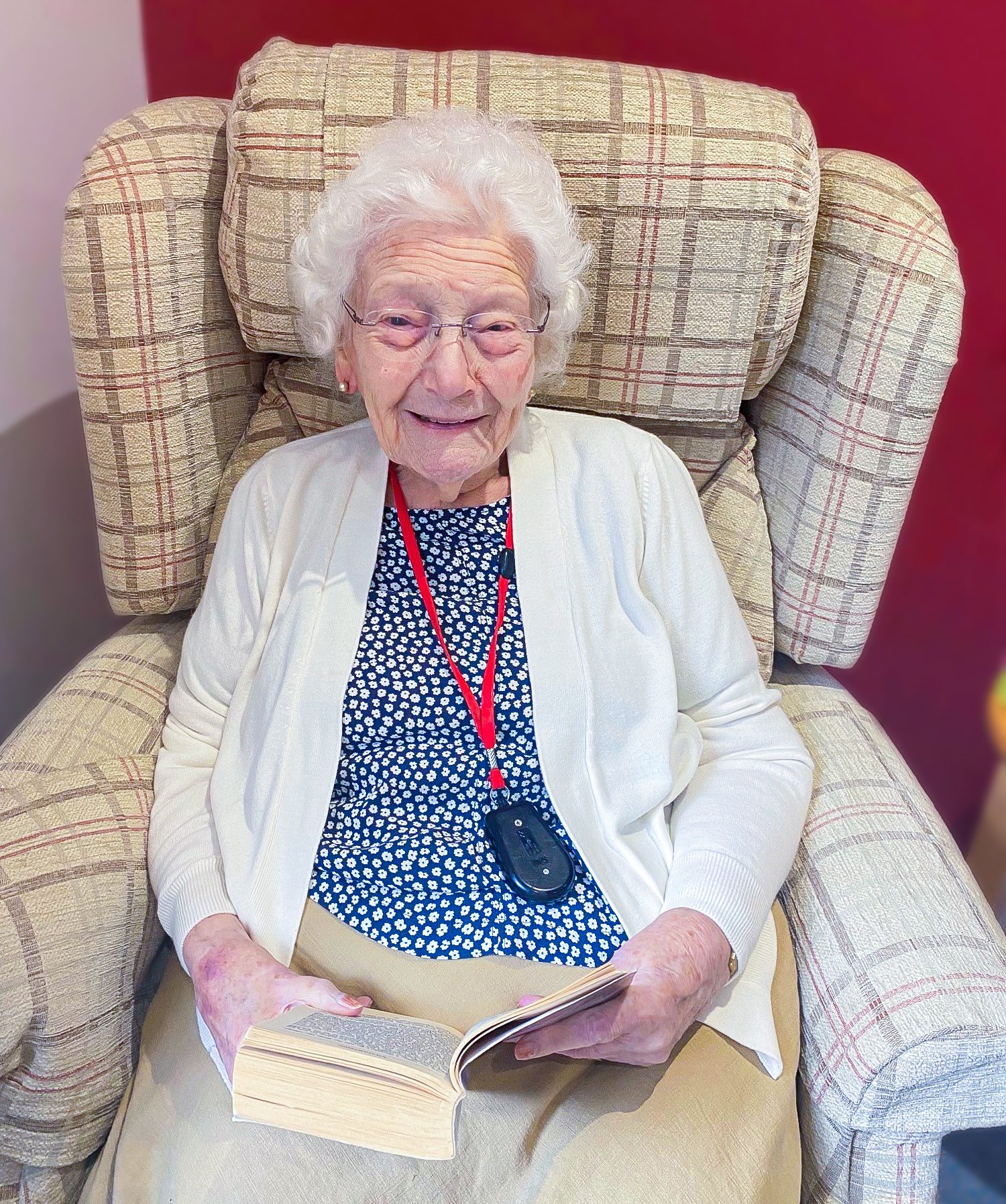 Woking care home resident Sheila sat in her favourite arm chair, smiling at the camera with a book in her hands. 