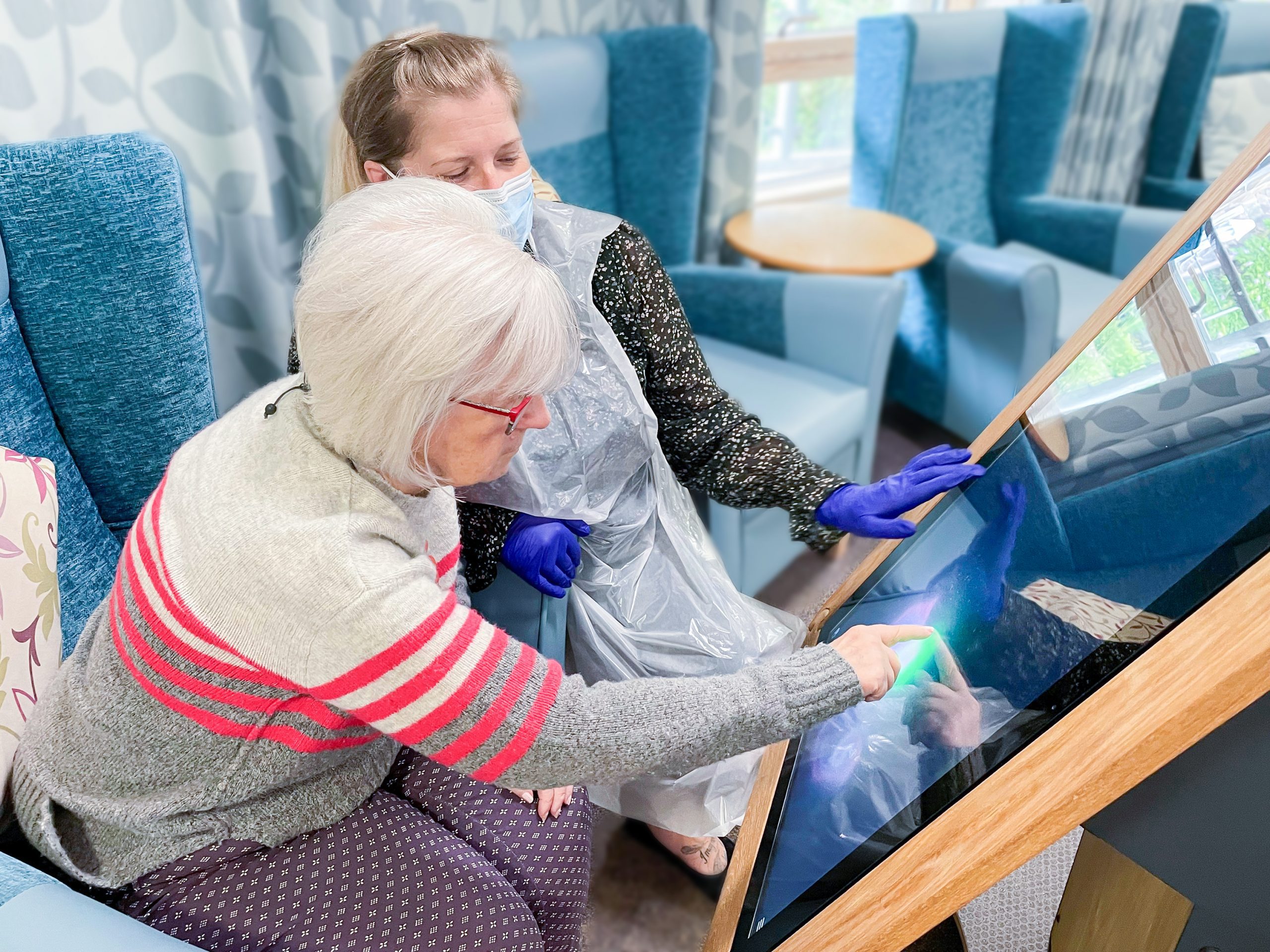 A care home resident and a member of staff using an interactive table.