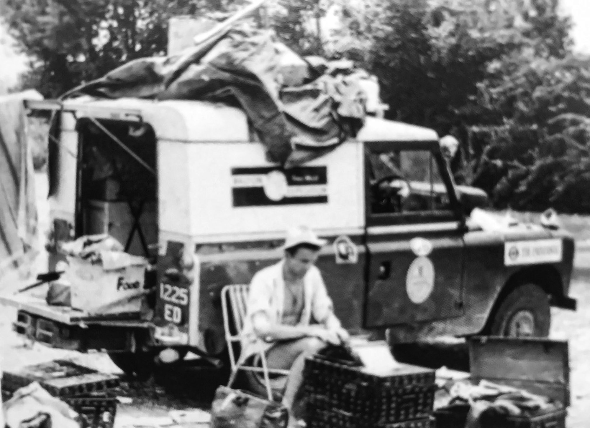 A black and white picture of Keith sat by the Land Rover during the trip. 