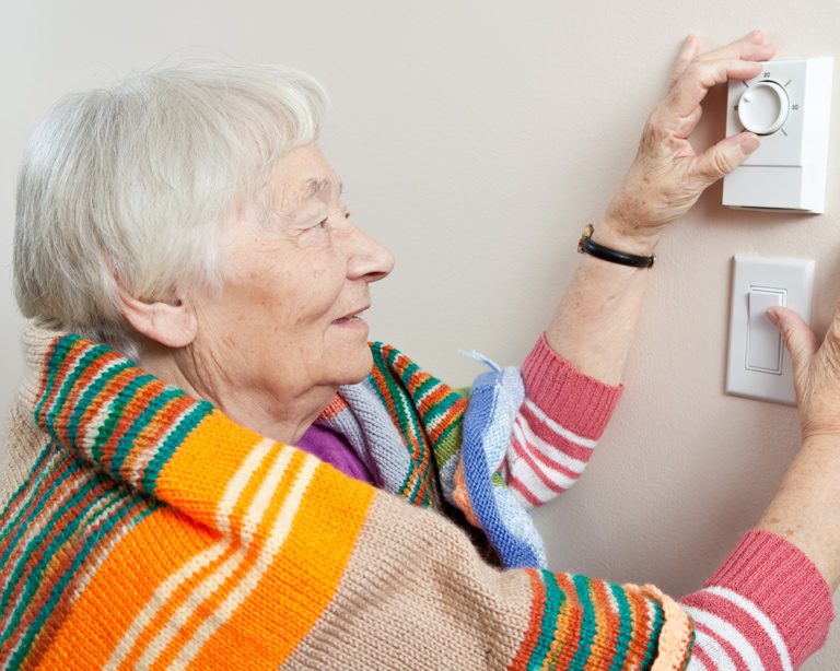Senior woman adjusting her thermostat