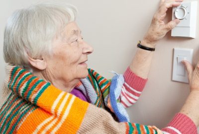 Senior woman adjusting her thermostat