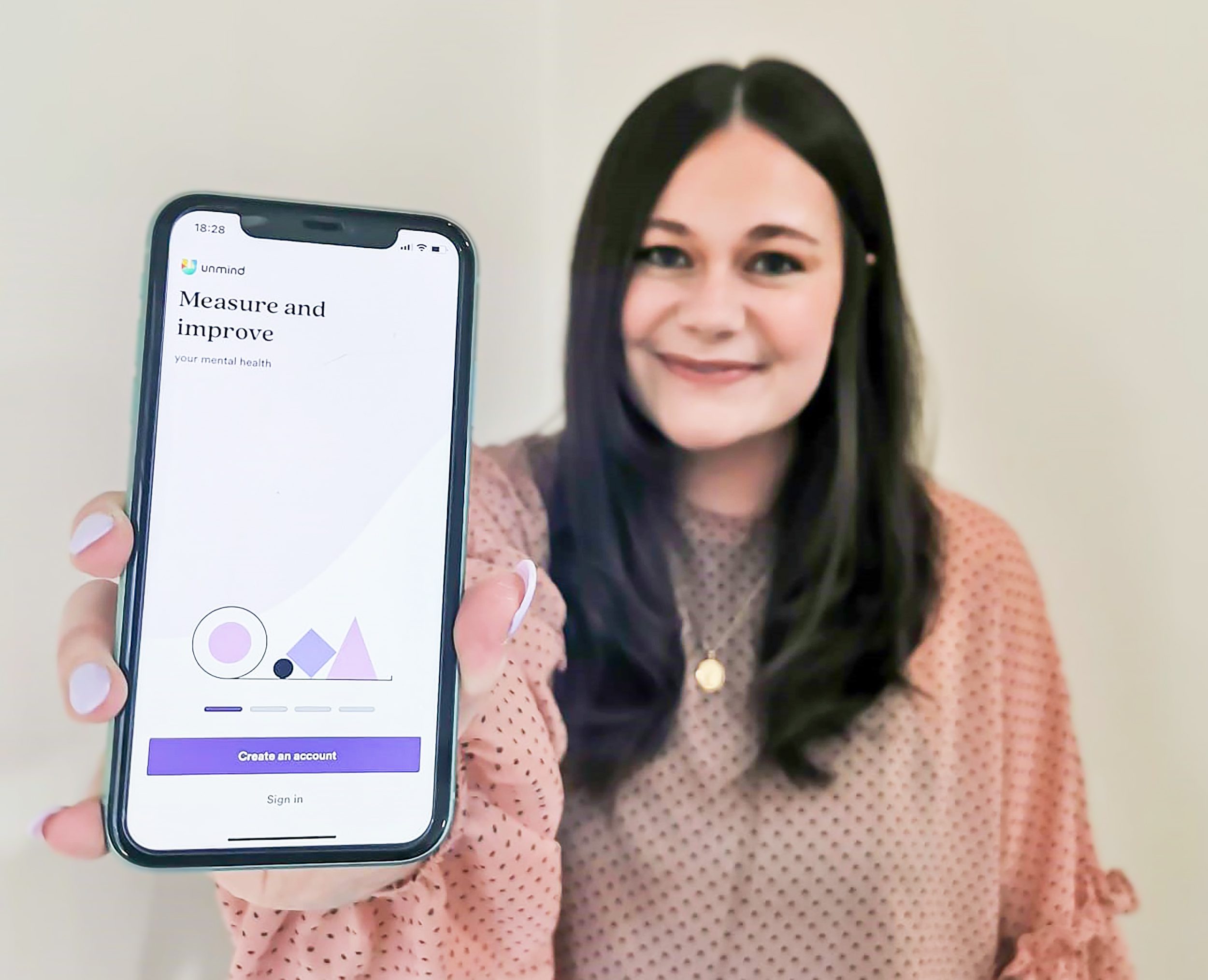 Learning and Development Advisor Rachel North holding her phone and showing the Unmind app. 