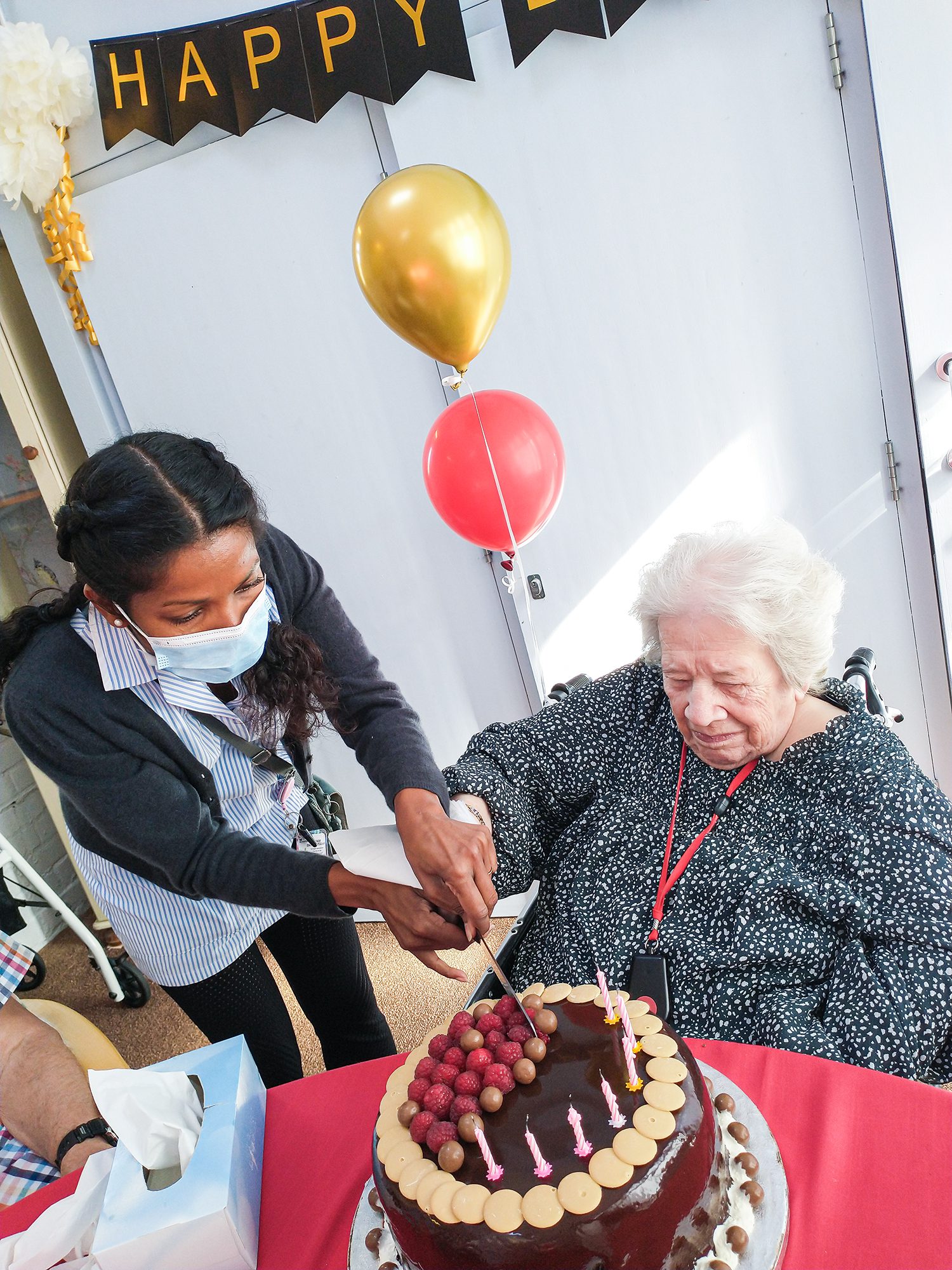 Joyce cutting her birthday cake with a member of staff from The Lawn care home.