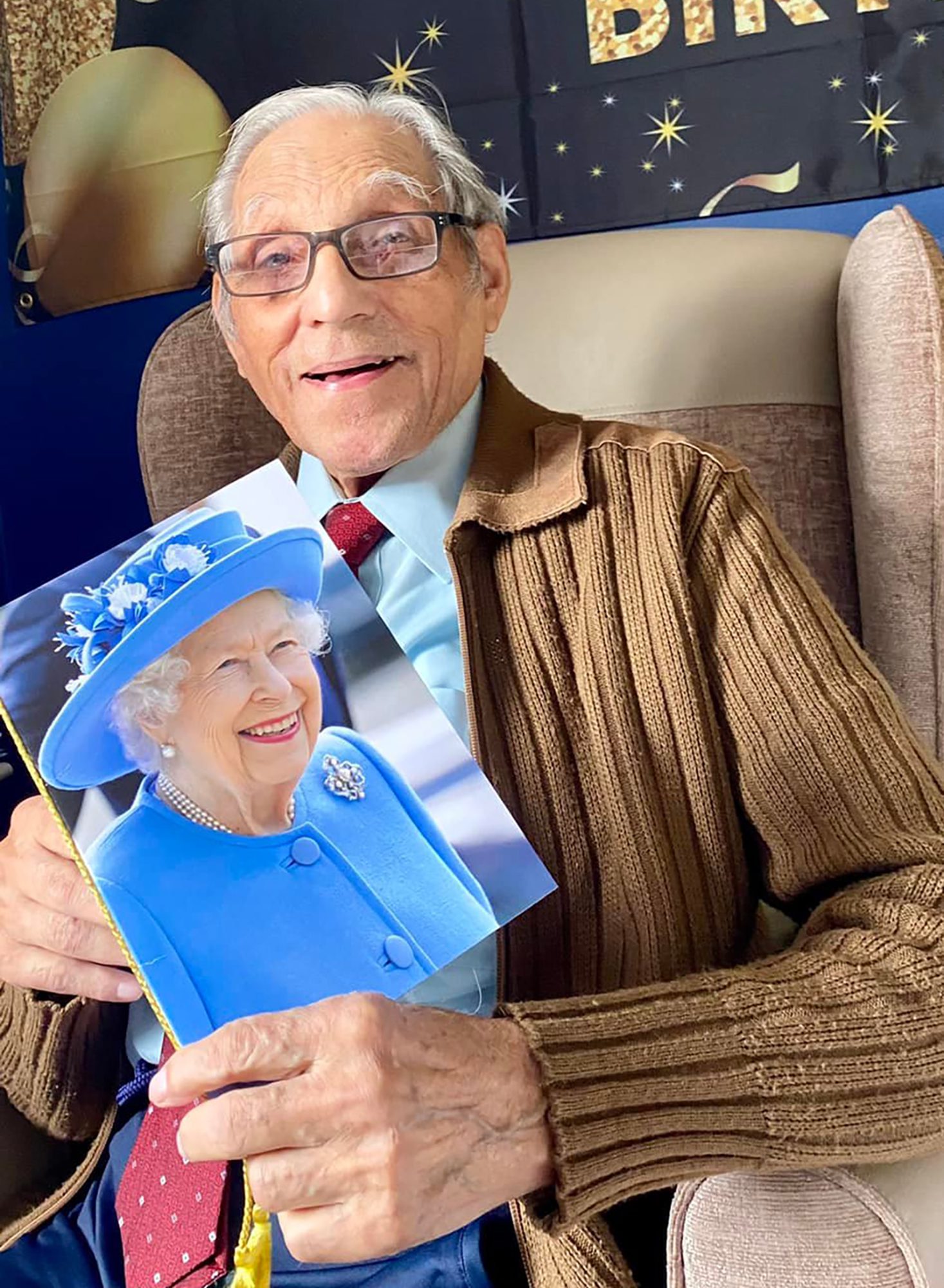 Centenarian Cedric on his birthday holding a card from HM Queen Elizabeth II, before her sad passing.