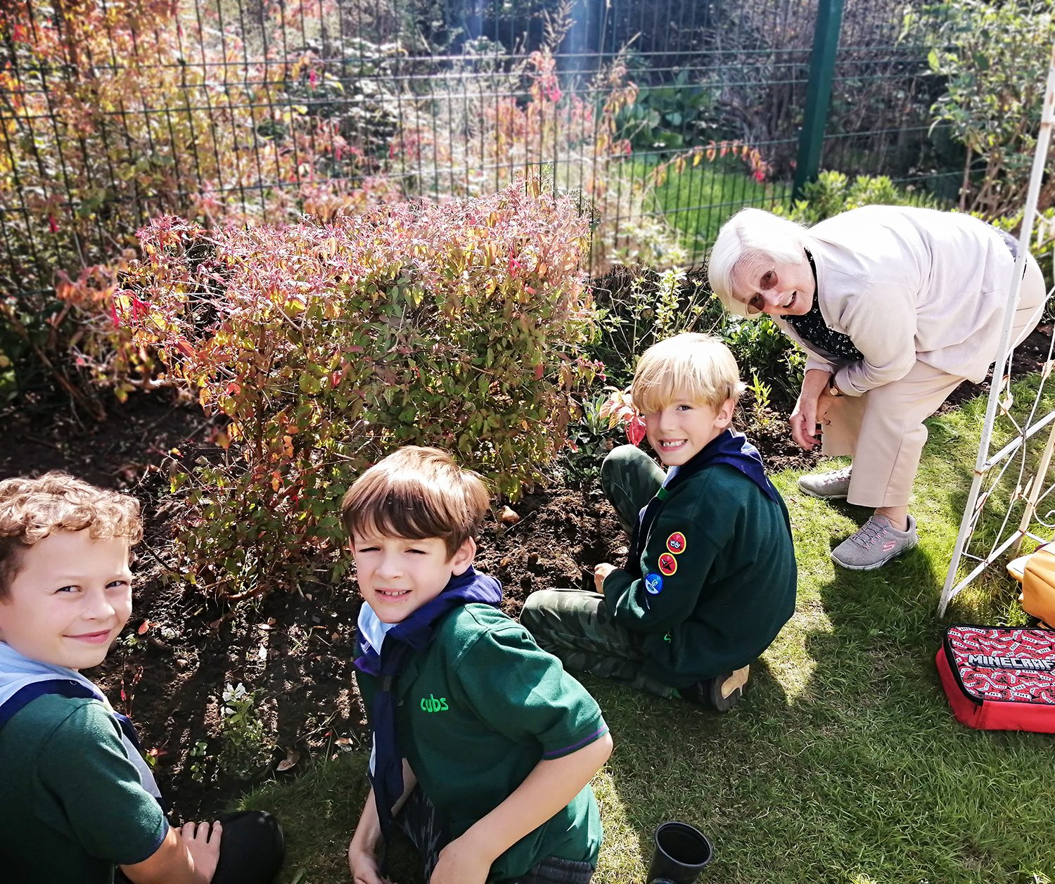 Three scouts gardening with an RNNH care home resident