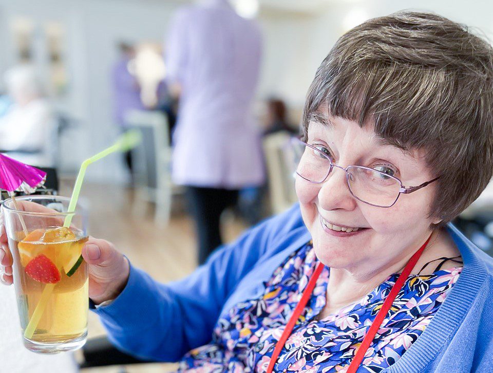 A smiling resident holding a drink. 