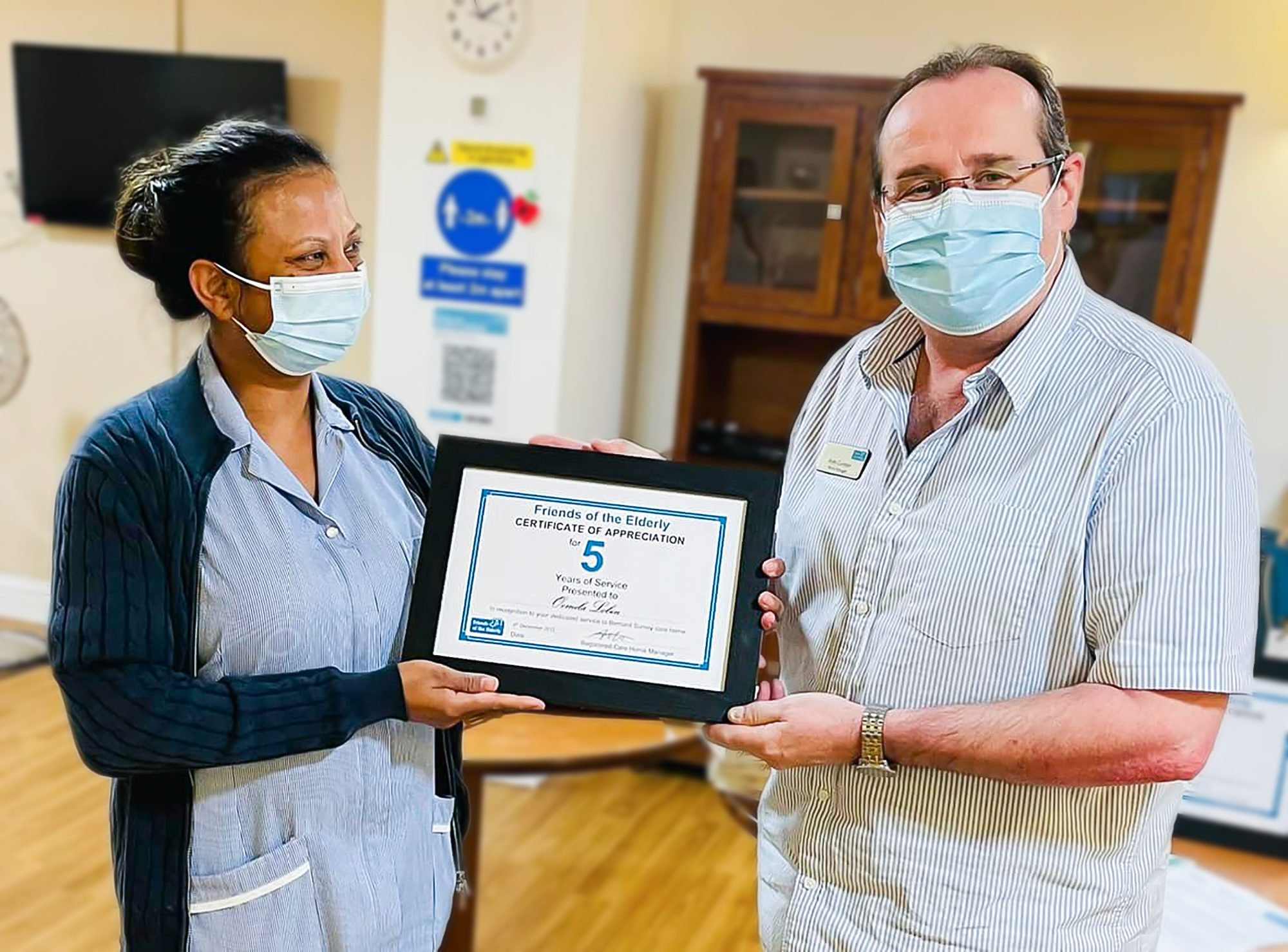 A Bernard Sunley care home staff member receiving a long service award from Care Home Manager Andy Cumper.