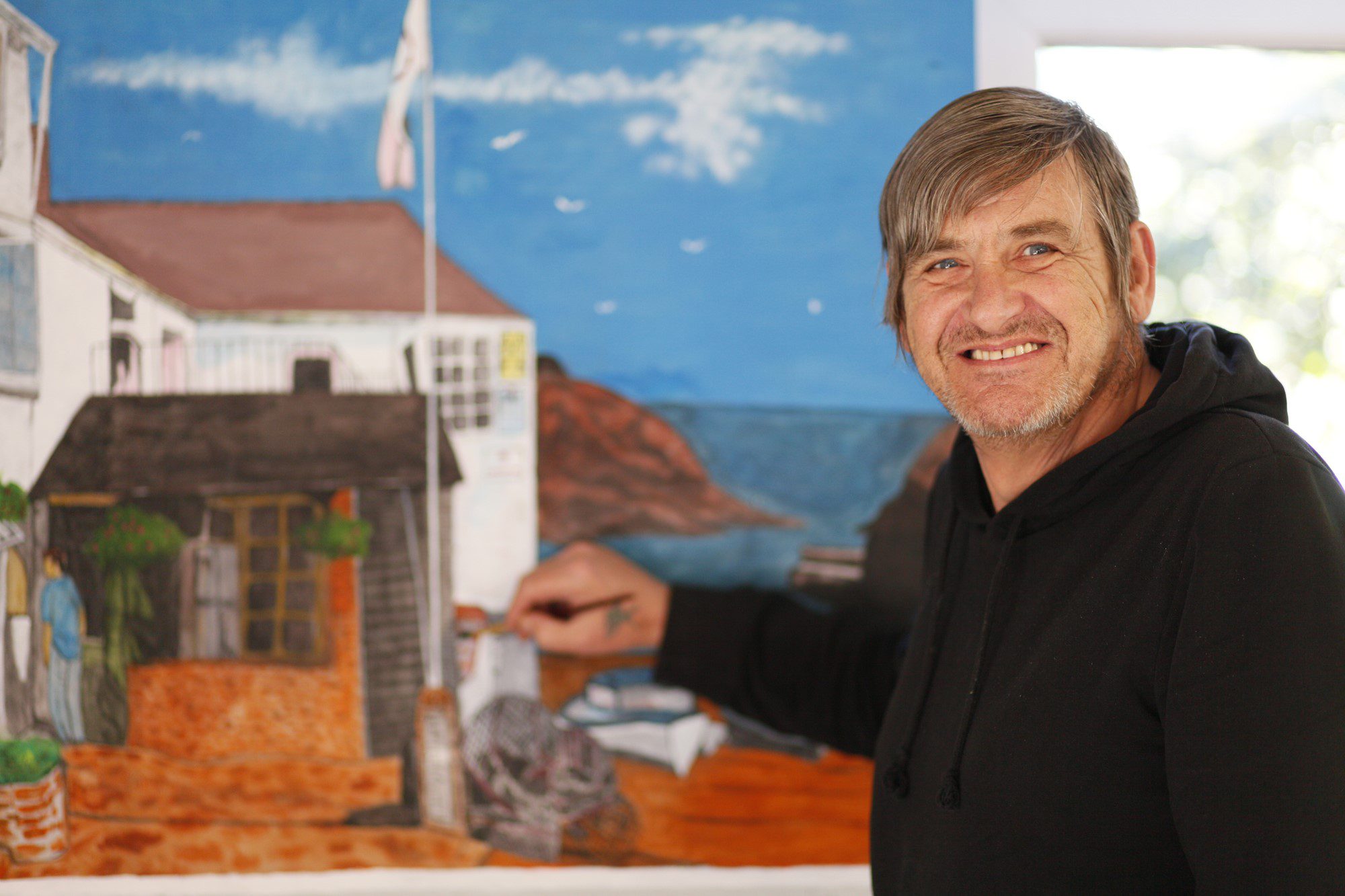 A Wallington Day Care client painting a mural on a wall. 