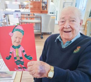2024 December highlights: A care home resident holds a card with a picture of himself as an elf. 
