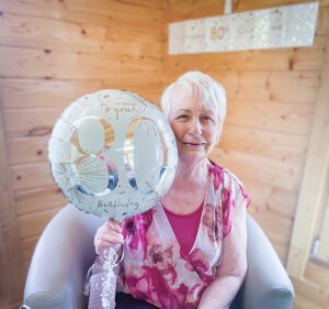 Marion on her birthday holding an 80th balloon.