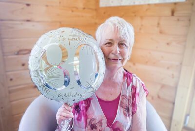 Marion on her birthday holding an 80th balloon.