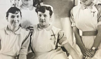 An old black and white photo of Jill when she was a nurse, sat with other nurses.