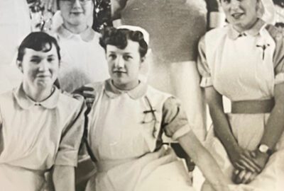 An old black and white photo of Jill when she was a nurse, sat with other nurses.