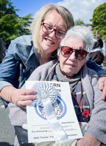 A member of the Team at Friend of the Elderly Malvern with a resident holding the silver medal and certificate.