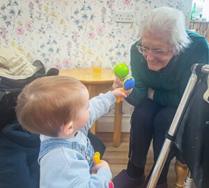 A resident and toddler play with toys together.