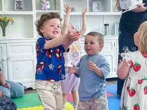 A group of children catching bubbles during the Musical Bumps session at our Luton care home. There are a mixture of ages and they are all smiling whilst trying to catch the bubbles.